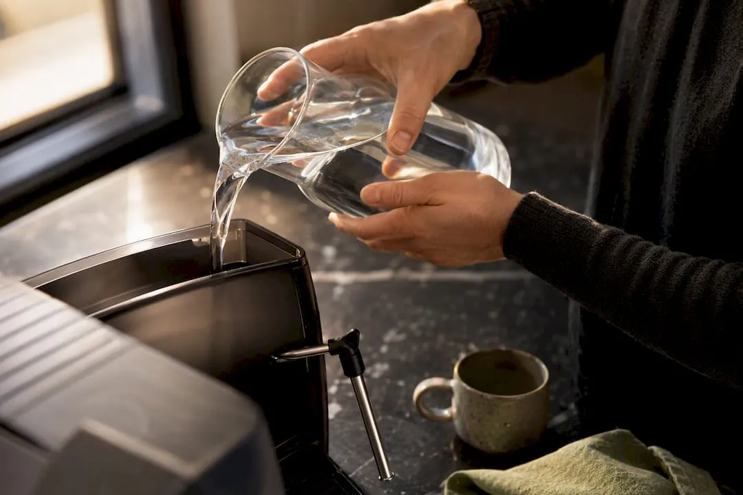 Pouring distilled water into espresso machine